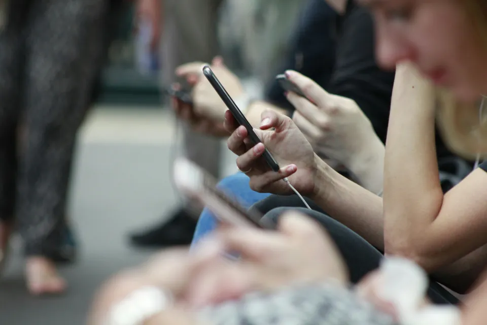 stock photo of people/hands holding cellphones - phone addiction - technology overdependence - by Robin Worrall on unsplash