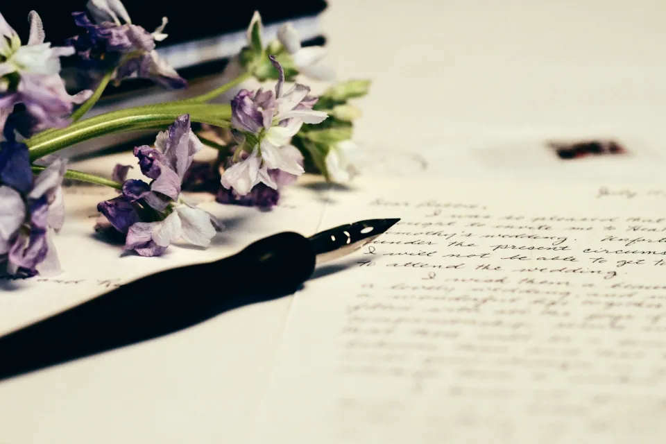 stock photo of pen and writing with purple flowers by Debby Hudson on unsplash